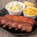 Smoked BBQ ribs served with macaroni salad, mac and cheese and cornbread