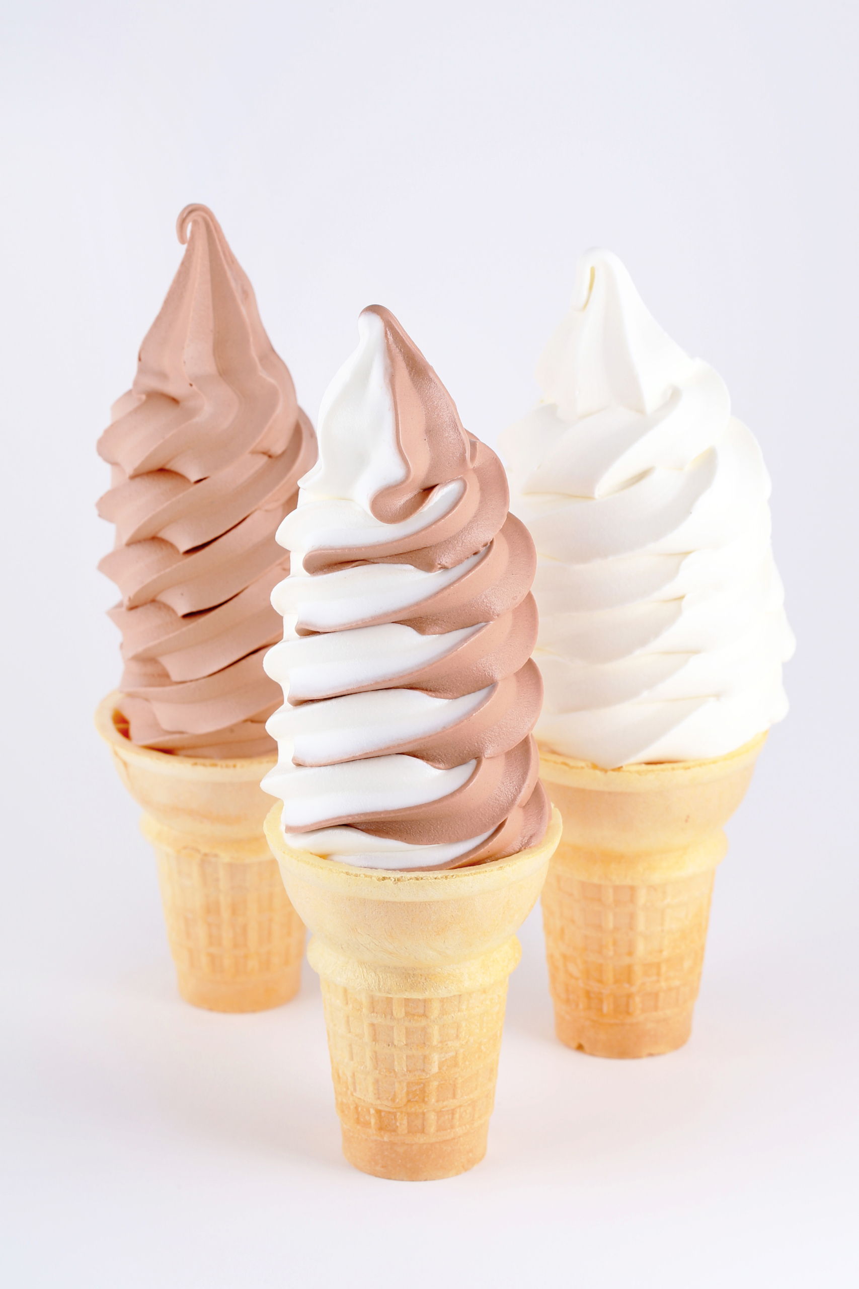 Three soft serve cones in chocolate, swirl, and vanilla flavors